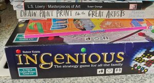 Ingenious board game on stack with books