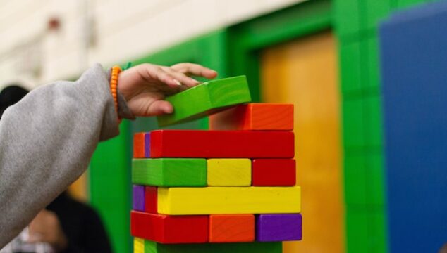 child building multi coloured wooden block tower